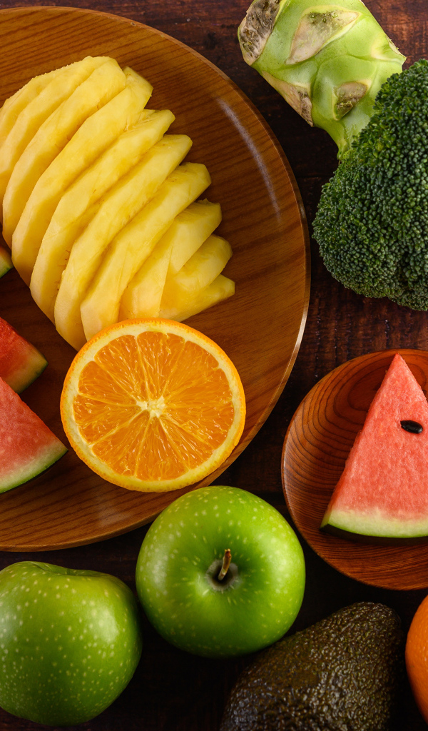 Фрукты и брокколи на столе с доской
