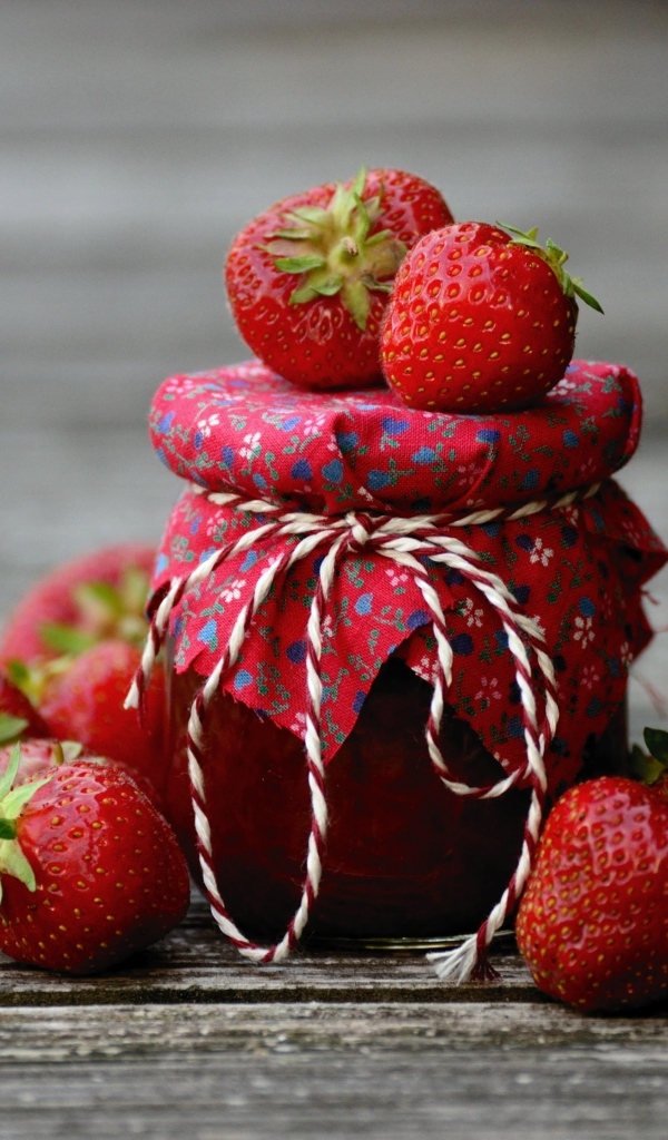 Банка джема на столе со свежими ароматными ягодами клубники