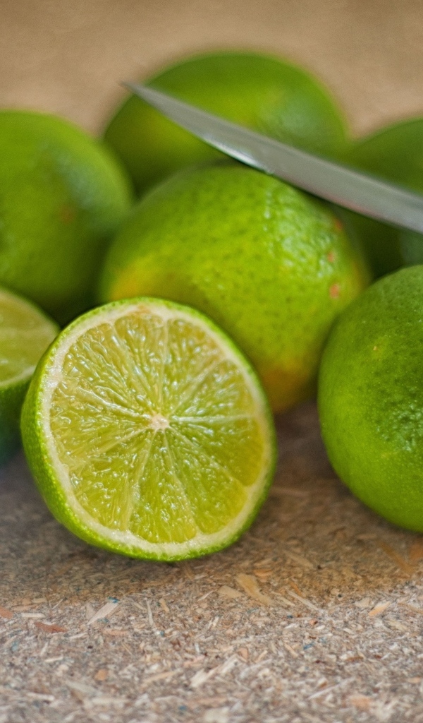 Много зеленых лаймов на столе с ножом