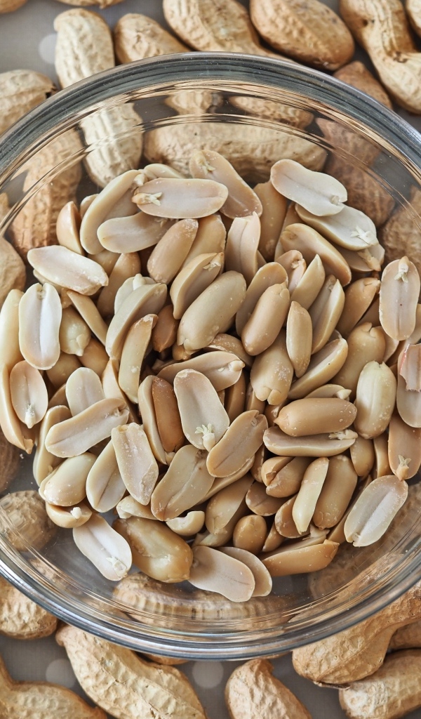 Арахис в стеклянной тарелке на столе 