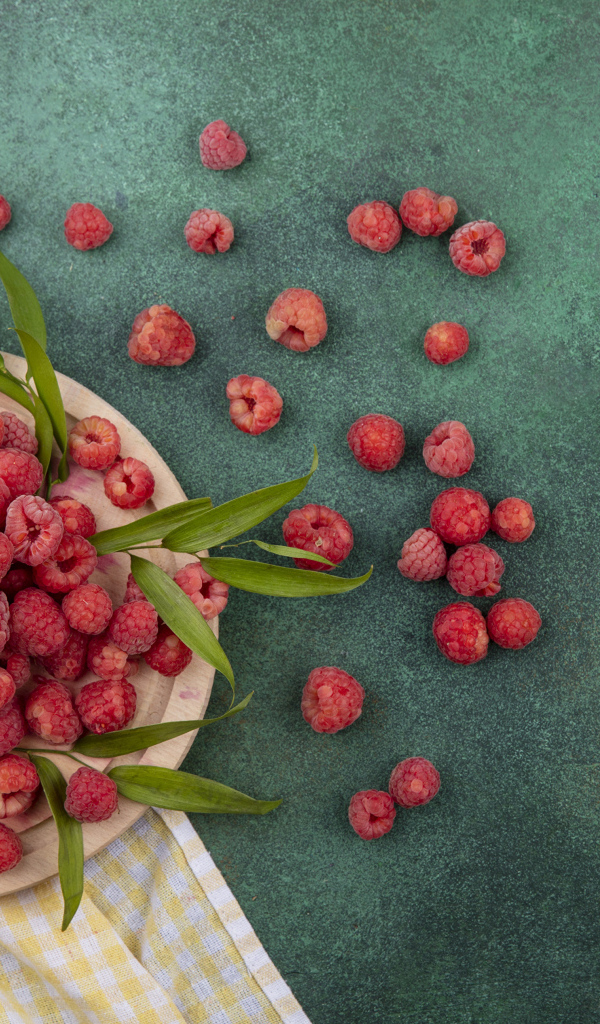 Красная малина с зеленой листвой на столе