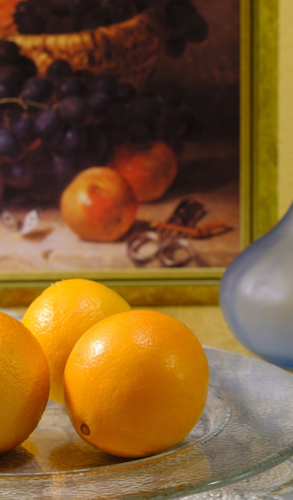 Три апельсина с вазами на столе