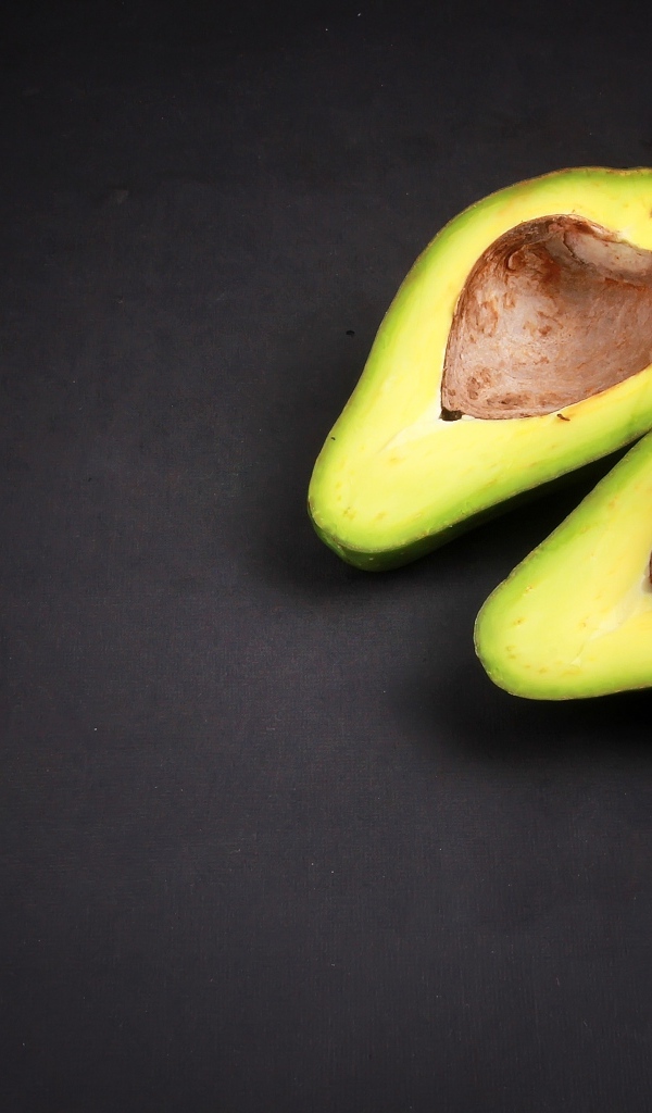 Две половинки зеленого авокадо на сером столе