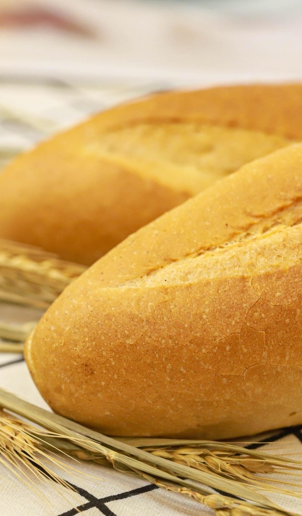 Два батона на столе с колосьями пшеницы