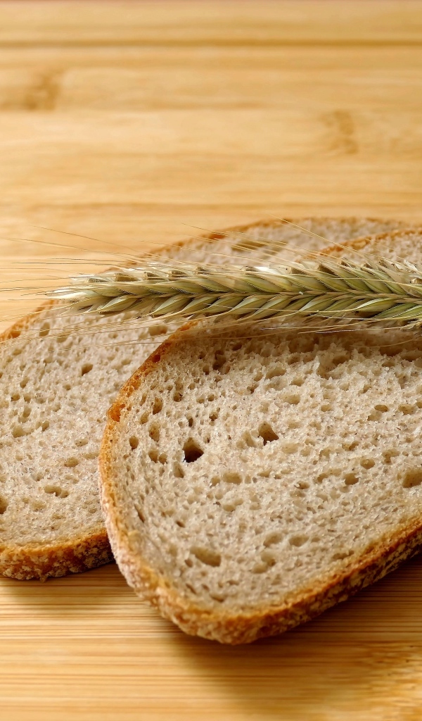 Два куска хлеба с колоском на деревянном столе