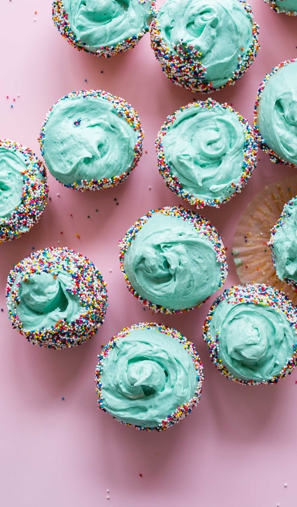 Аппетитные кексы с голубым кремом на розовом столе