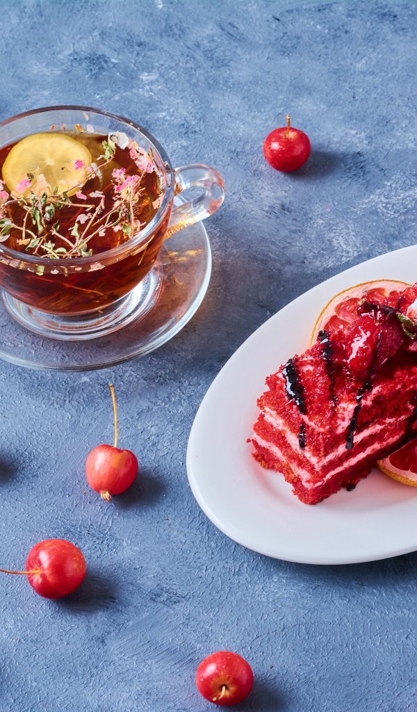 Аппетитный кусок торта на столе с чаем и ягодами черешни