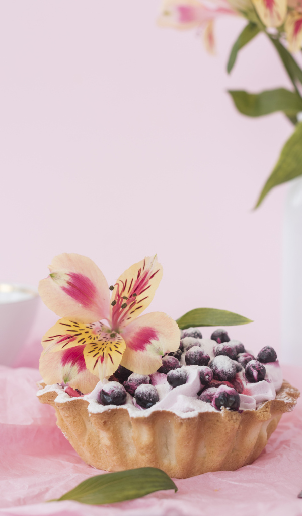 Черничное пирожное с цветами альстромерии на розовом фоне