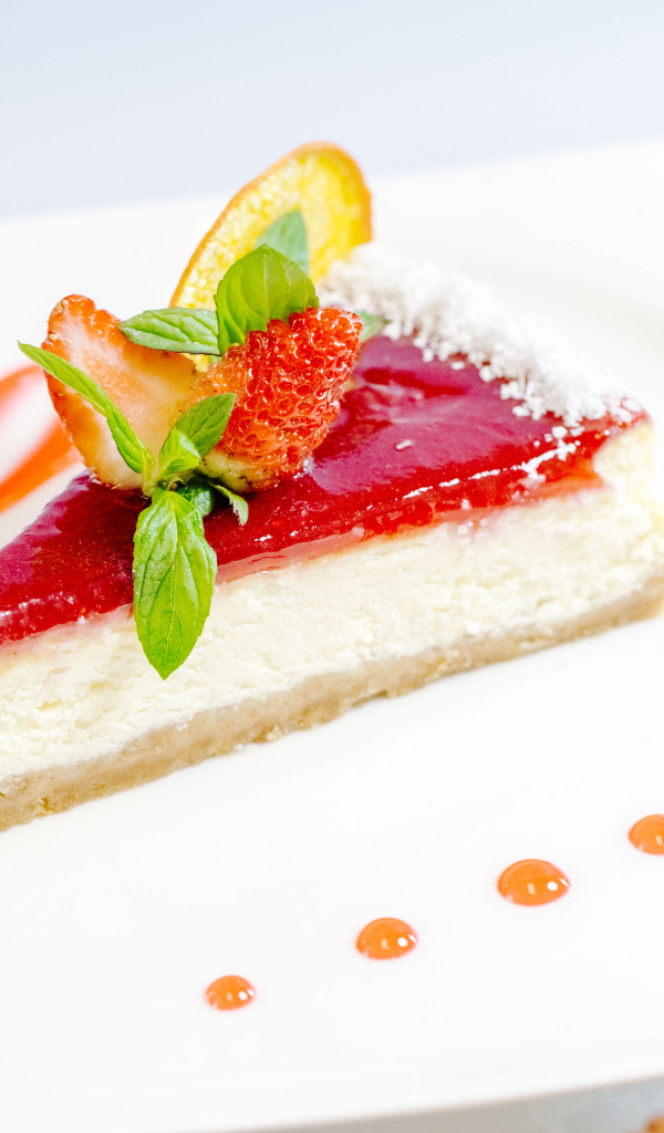 Чизкейк с клубничным джемом и ягодами на белой тарелке