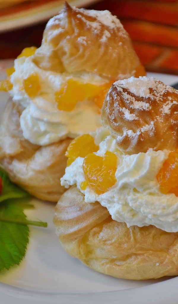 Заварное печенье со взбитыми сливками на тарелке с ягодами