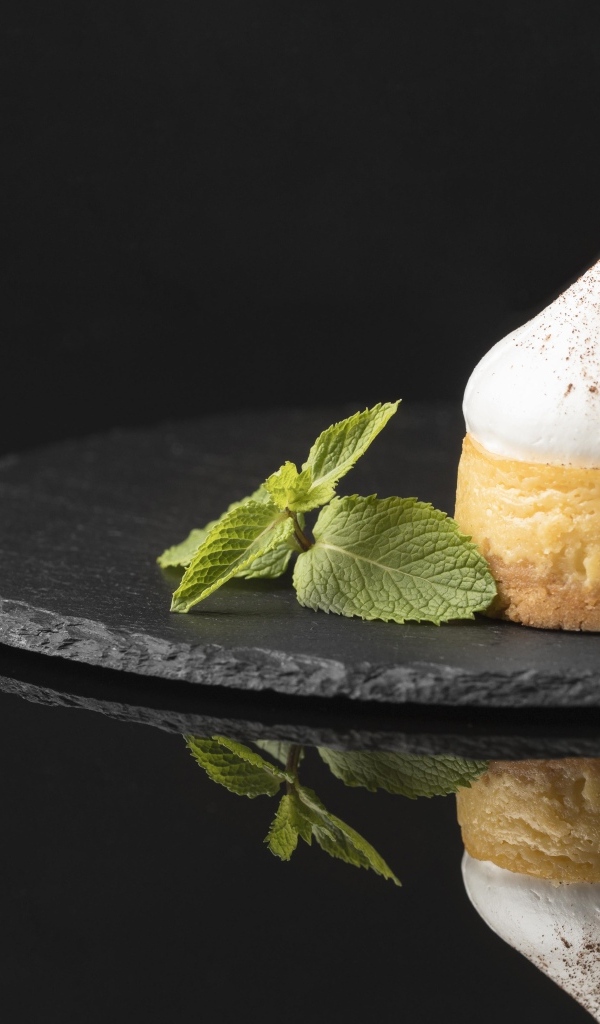 Десерт с кремом и листьями мяты на черном фоне