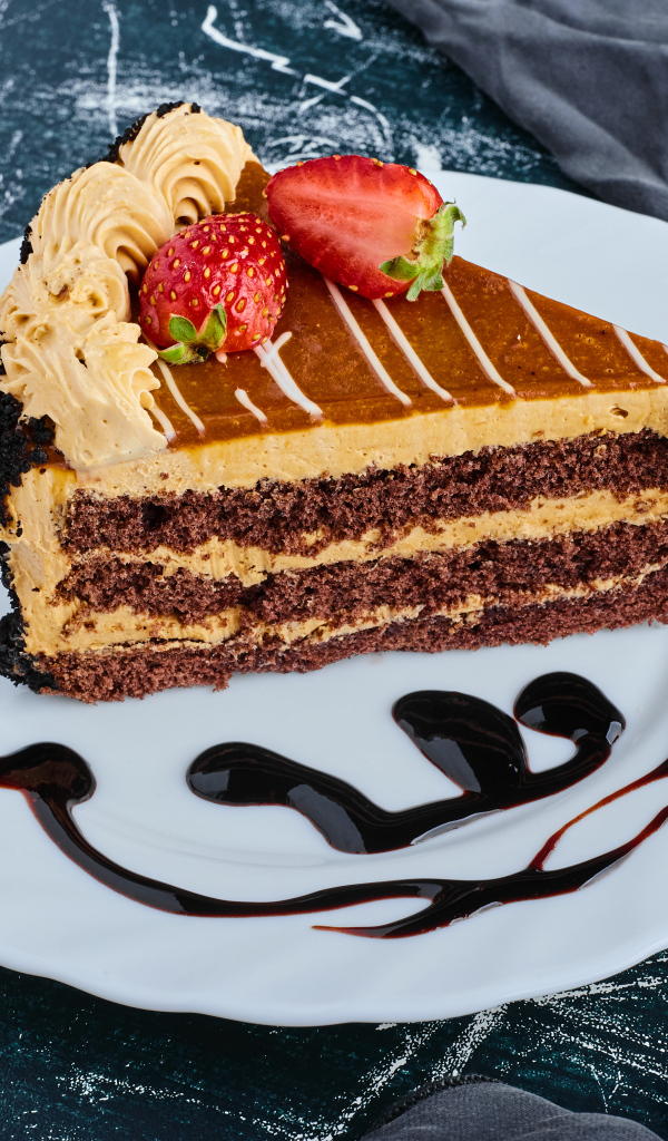 Кусок торта с клубникой на большой белой тарелке