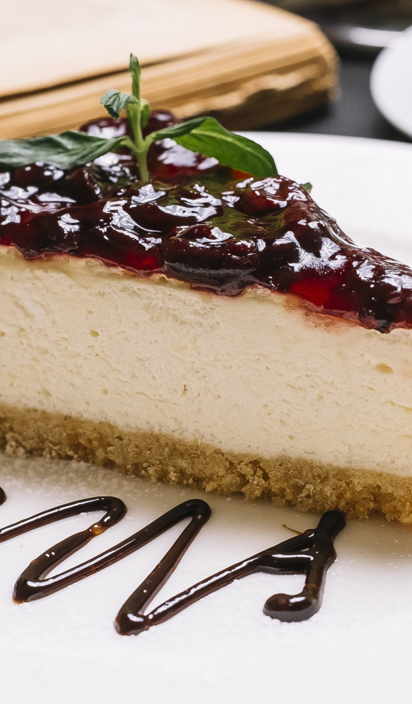 Кусок чизкейка с джемом на белой тарелке