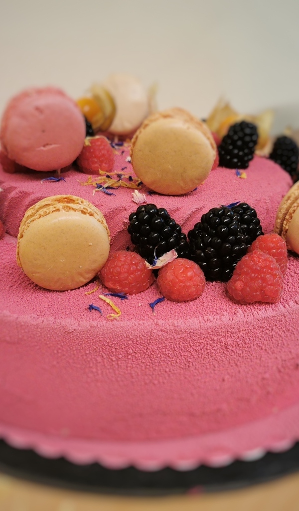 Розовый торт украшен печеньем и ягодами