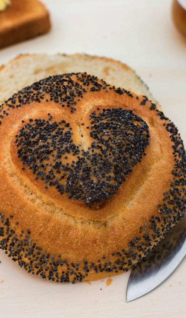 Булочка с маком с нарисованным сердцем на столе