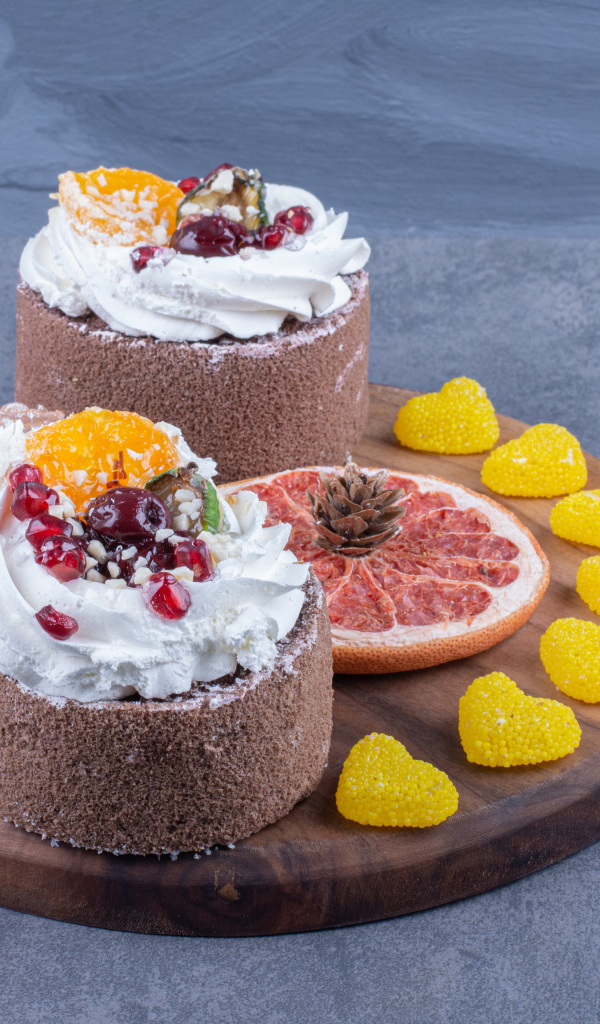 Два пирожных на деревянной доске с мармеладными конфетами