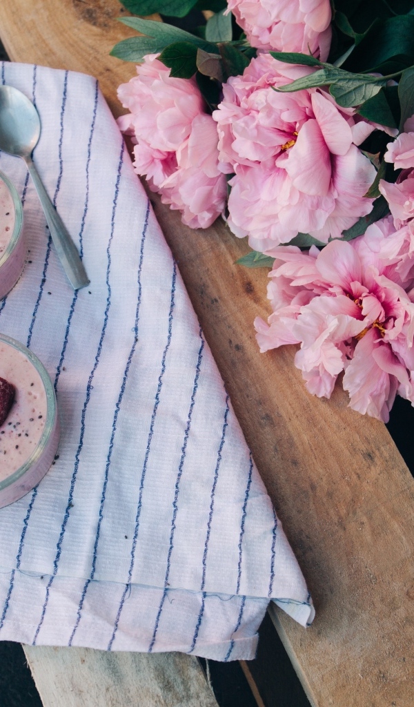 Два стакана с десертом на лавке с букетом пионов