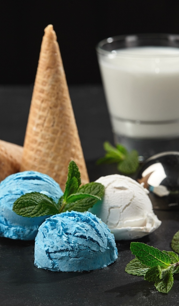 Вафельный рожок с шариками мороженого, мятой и молоком на столе