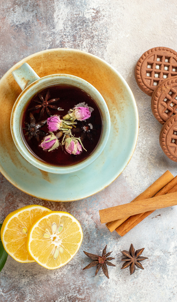 Чашка ароматного чая на столе с лимоном, печеньем и пряностями