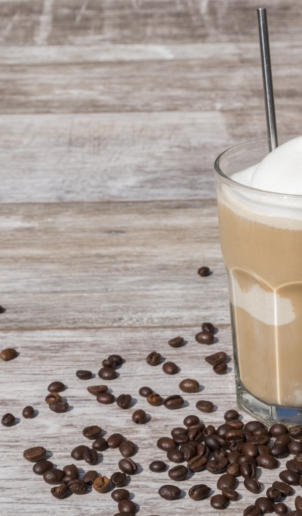 Кофе с мороженым в стакане на столе с кофейными зернами