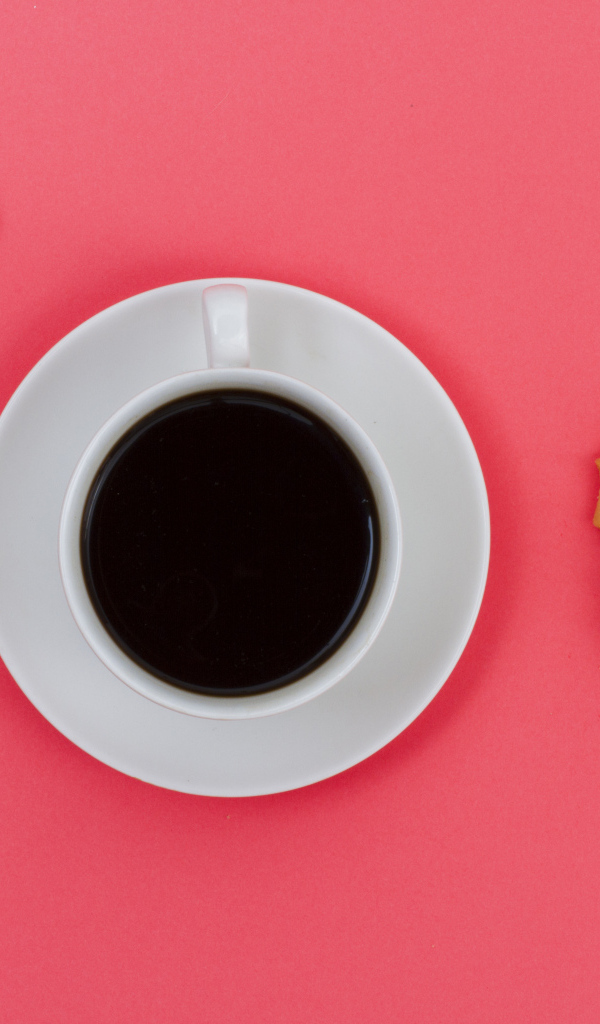 Чашка кофе на розовом фоне с цветком и печеньем