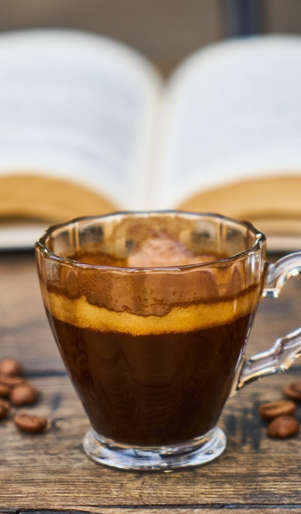 Чашка кофе на столе с зернами и книгой