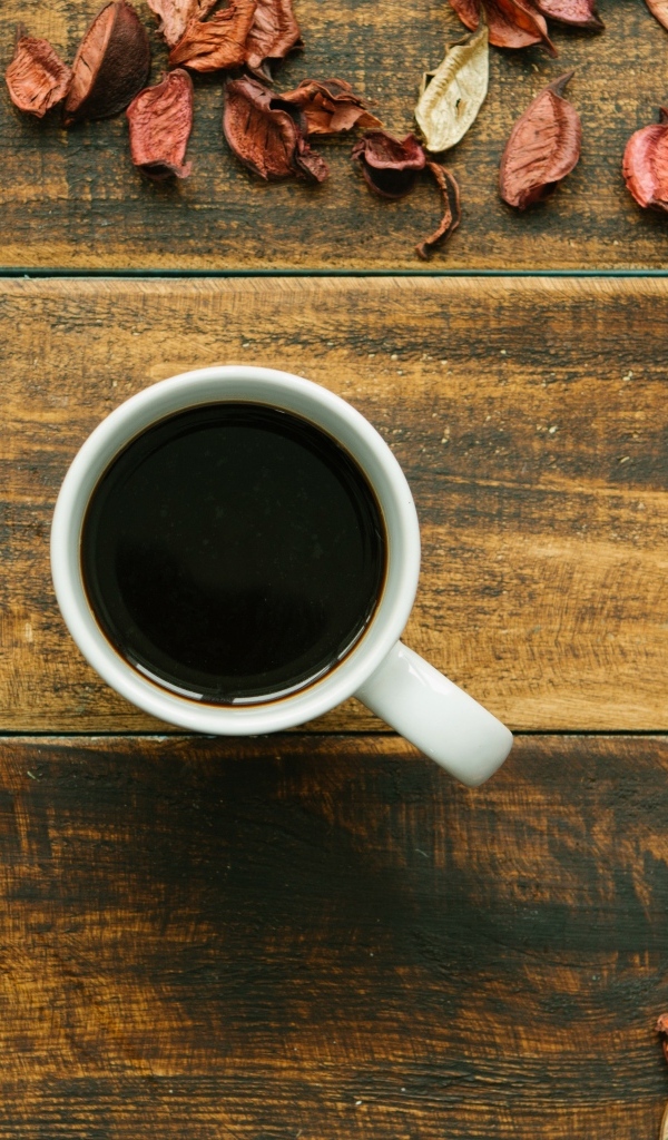 Чашка кофе с опавшими листьями на деревянном столе