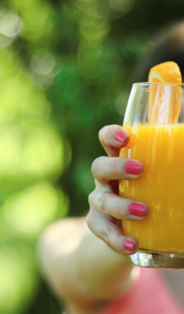 Девушка держит стакан апельсинового сока в руке