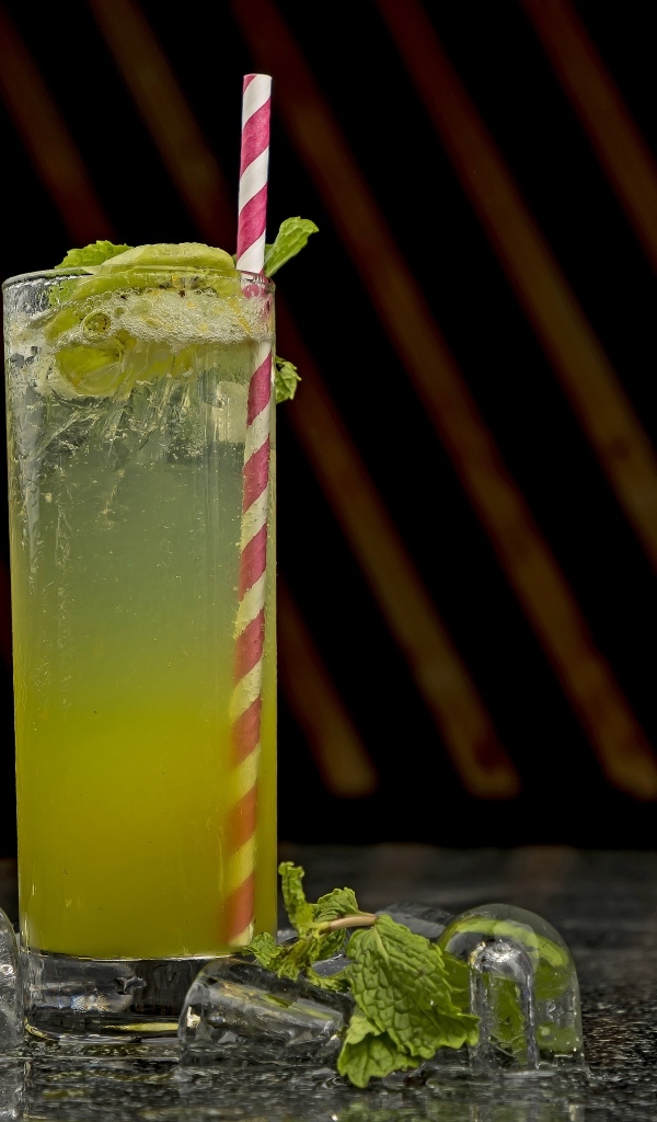 Зеленый коктейль мохито в высоком стакане со льдом