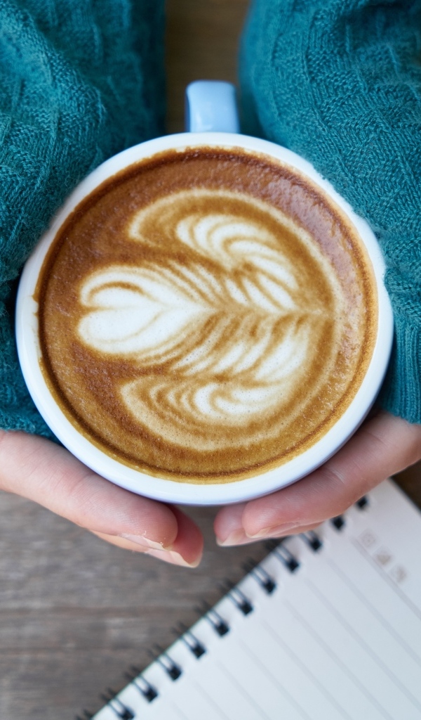 Горячая чашка кофе на столе в руках девушки