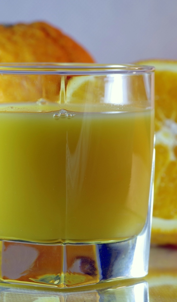 Оранжевый апельсиновый сок в стакане на столе с плодами