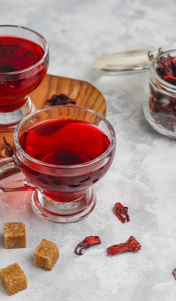 Две чашки чая каркаде на столе с заваркой 