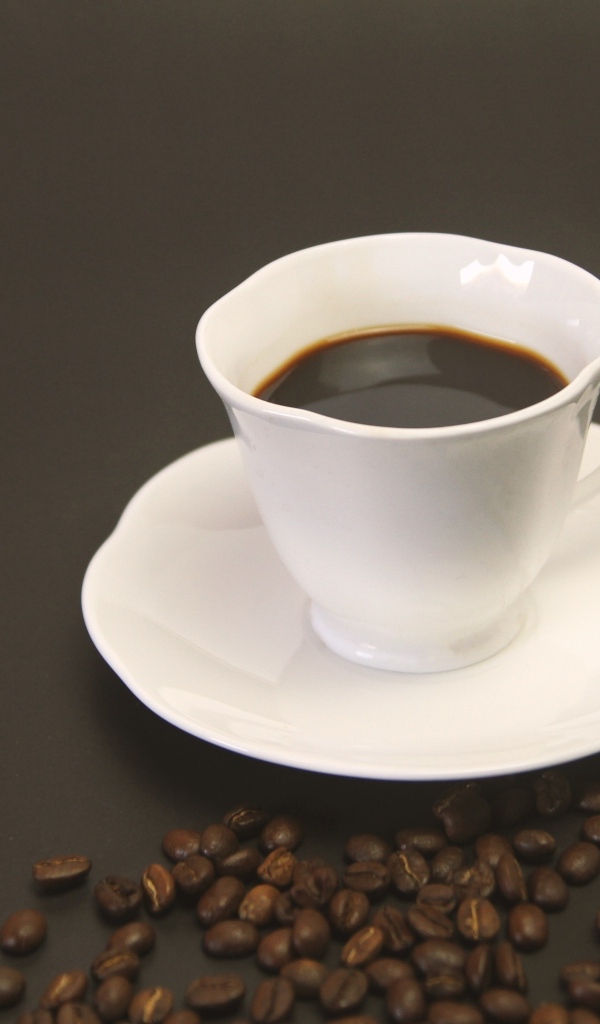 Белая чашка с кофе на столе с зернами