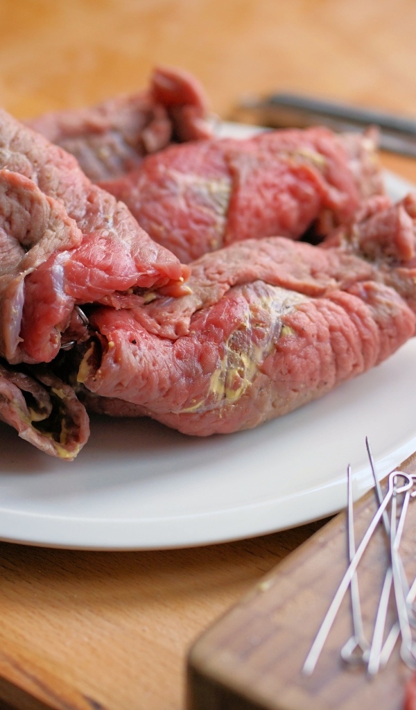 Рулетики из свинины на большой белой тарелке