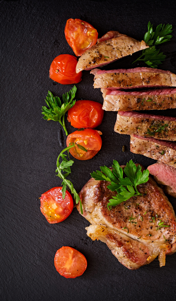 Нарезанный кусок мяса с помидорами и зеленой спаржей