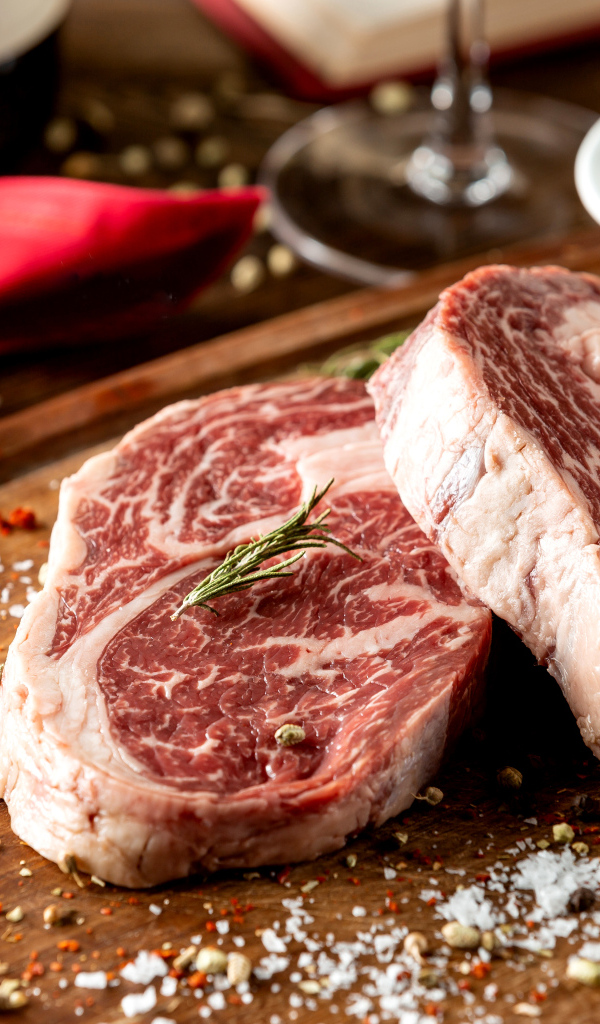 Два куска аппетитного стейка на столе со специями