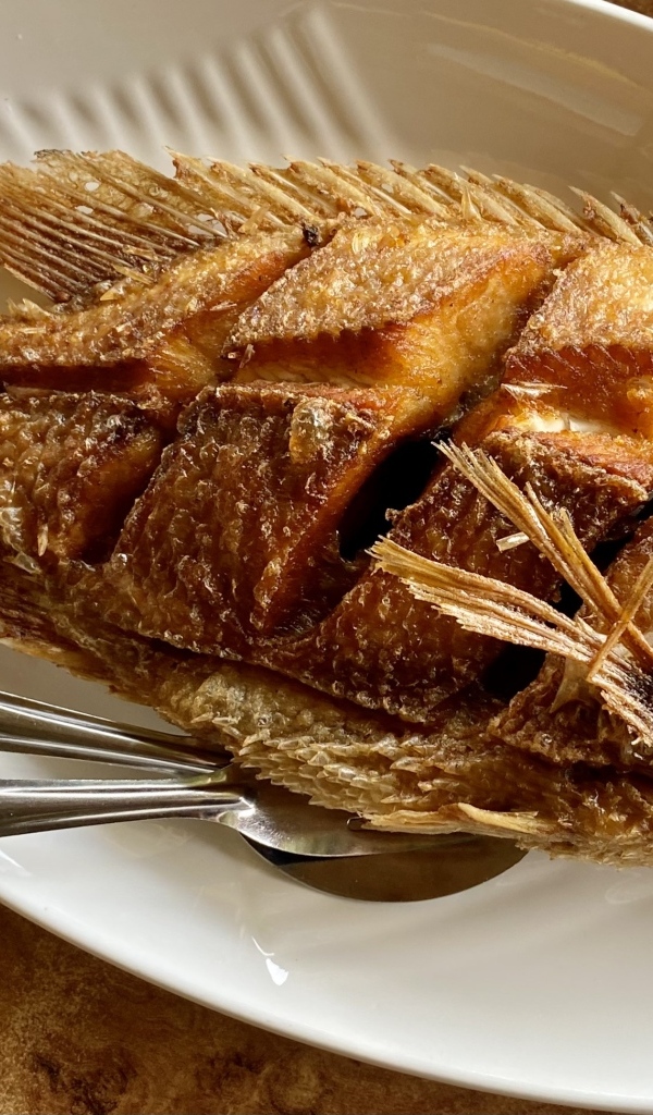 Запеченный карп на белой тарелке