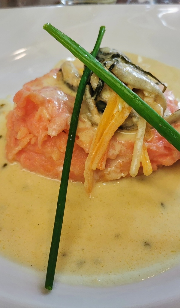 Красная рыба с соусом на тарелке с зеленым луком