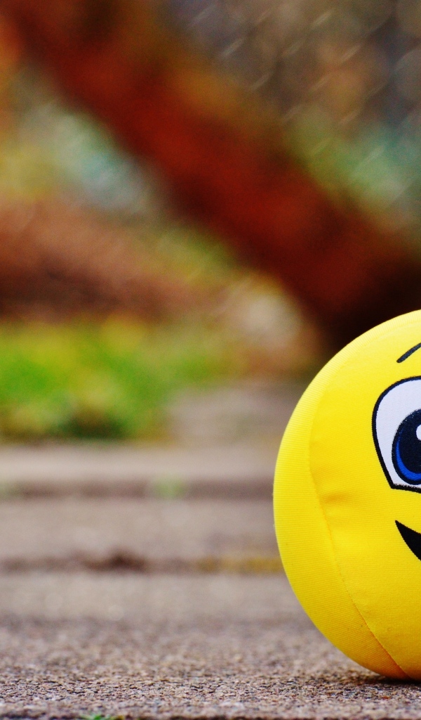 Желтый мягкий мяч смайл на дороге