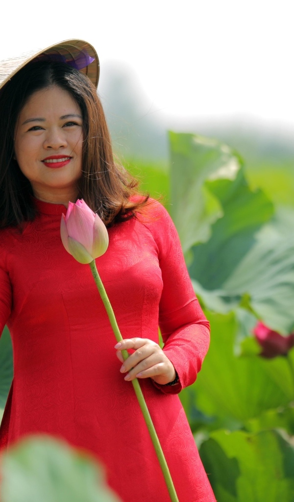 Девушка азиатка в красном платье у цветов лотоса