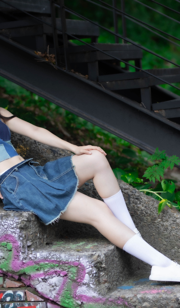 Девушка азиатка в юбке лежит на лестнице