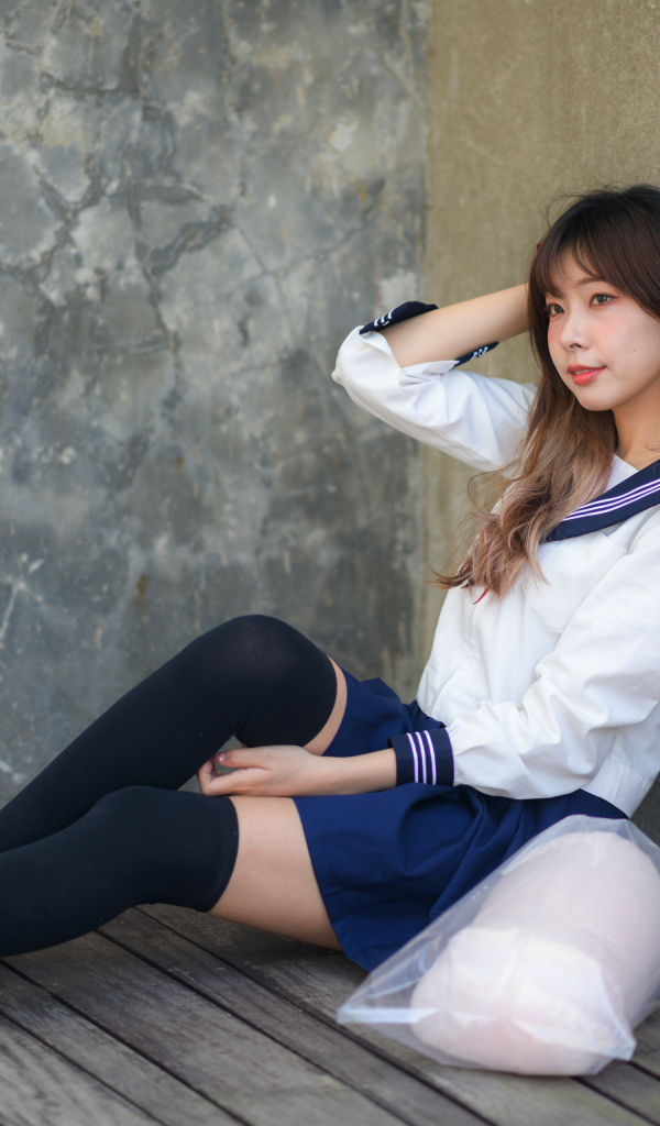 Азиатка в черных чулках сидит у стены