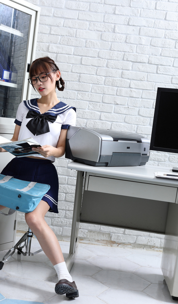 Девушка азиатка в форме сидит в офисе