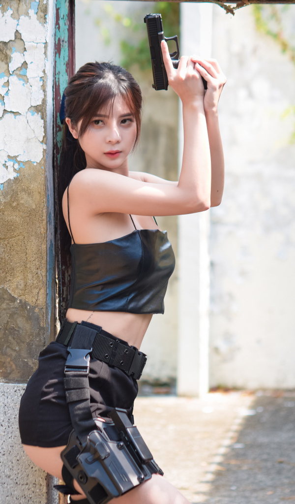 Девушка азиатка с пистолетом в кожаном костюме