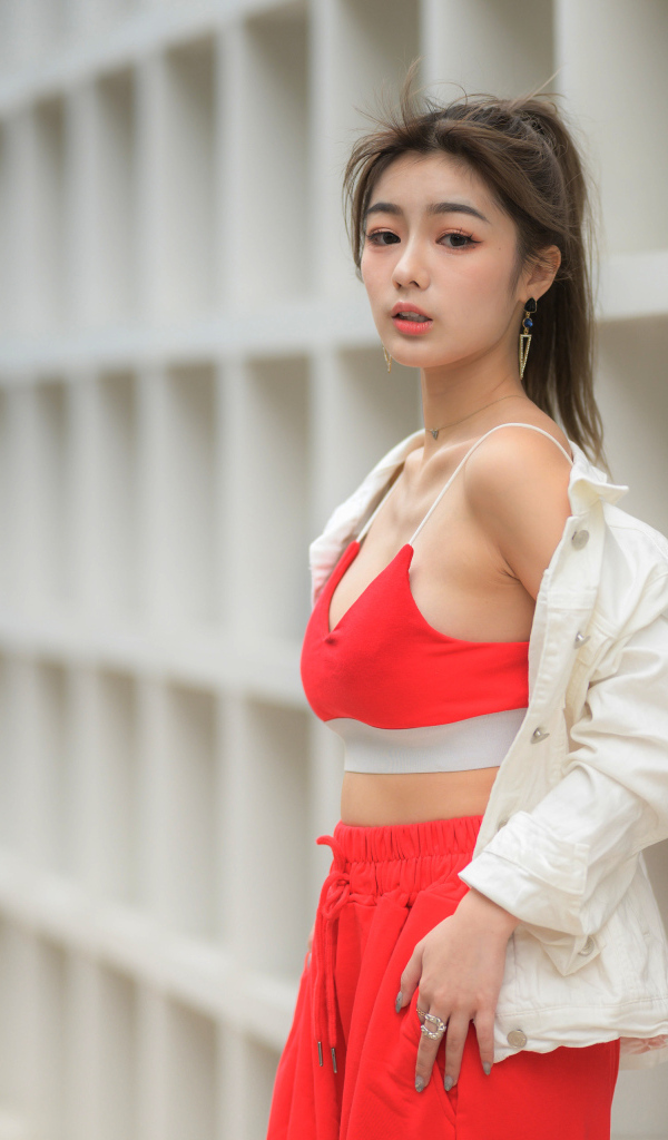 Азиатка в красном спортивном костюме стоит у стены