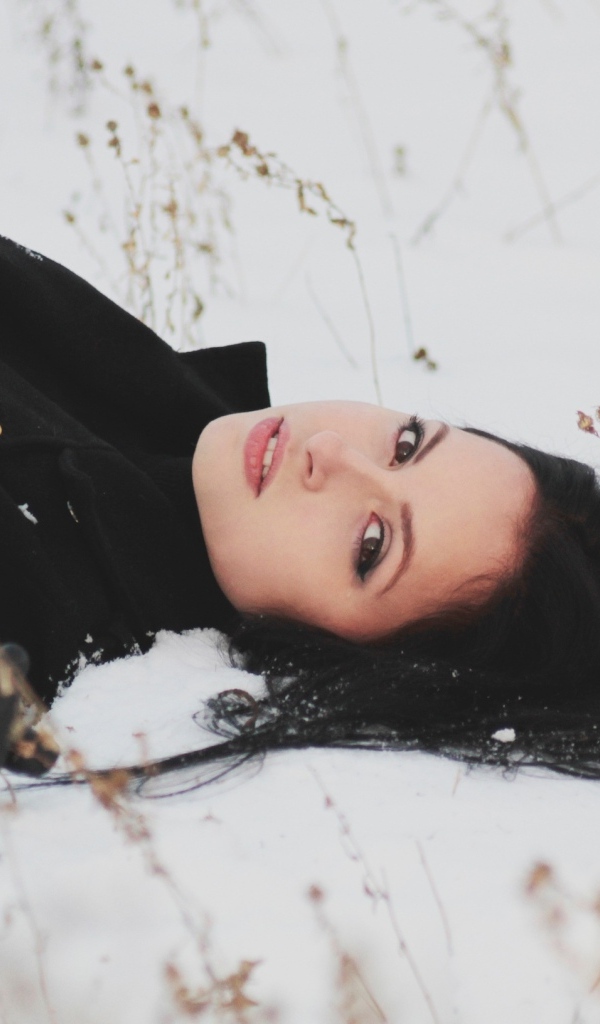 Красивая брюнетка лежит на холодном снегу