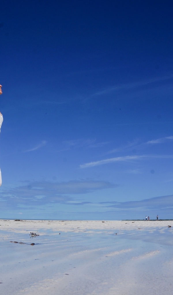 Красивая девушка в белом платье на мокром песке