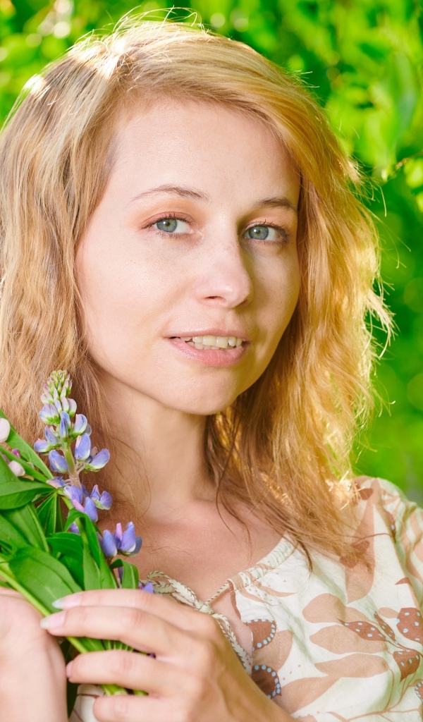 Красивая девушка с цветами люпина в руке