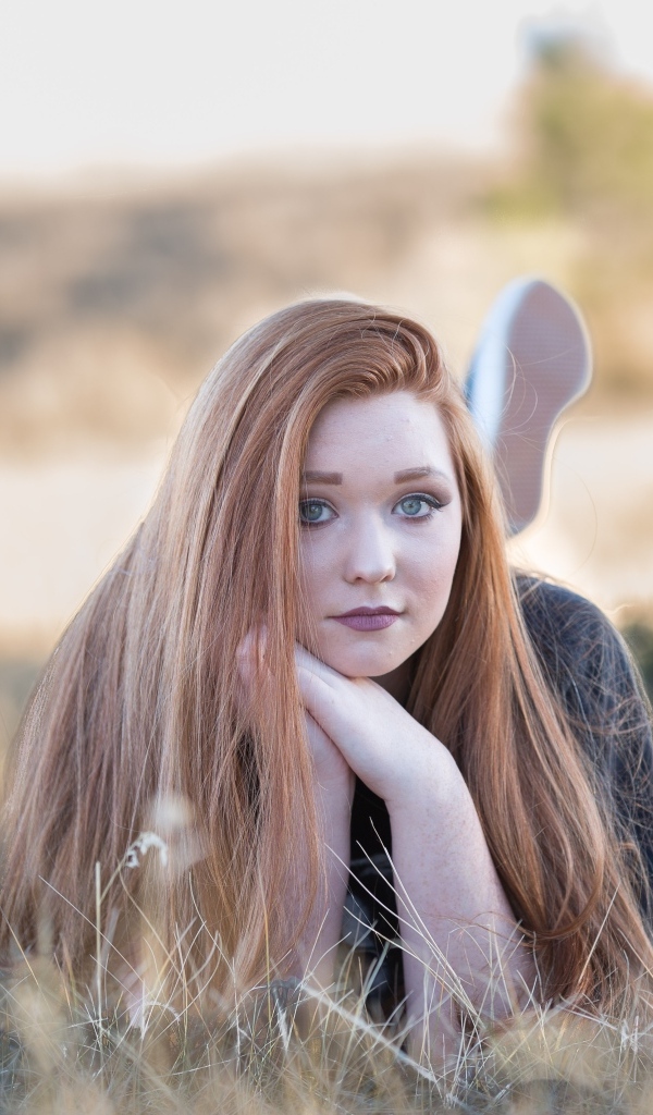 Красивая рыжеволосая девушка лежит на траве