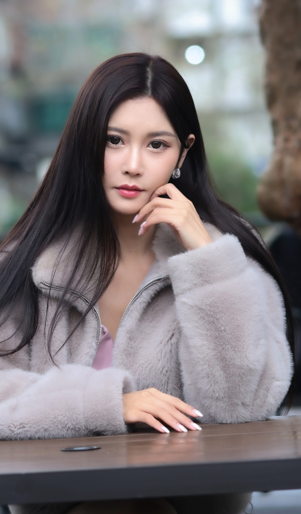 Кареглазая азиатка сидит в парке за столом